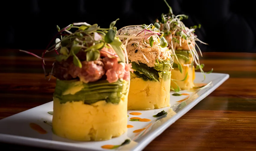 Traditional Peruvian dish called Causa made of mashed potato with aji hot pepper and lime juice and filled with vegetables corn, peas, carrots and mayonnaise 